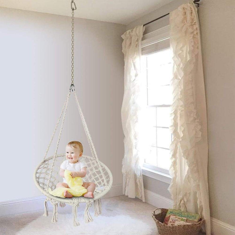 child sits on the single chair swing in the room